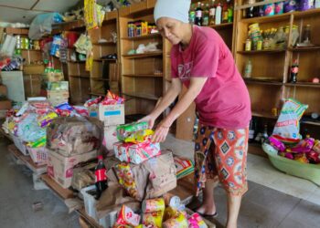 Norlaila Ali membersih dan menyusun kembali barangan kedai runcitnya yang sempat diselamatkan dalam kejadian banjir di Kampung Sungai Timun, di sini, semalam. – UTUSAN/NOR AINNA HAMZAH