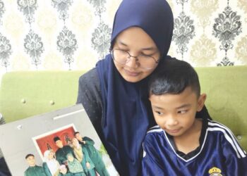 MARIZATI Hamdan menunjukkan gambarnya sekeluarga ketika ditemui di rumahnya di Taman Pedas Indah, Rembau, Negeri Sembilan, kelmarin. - UTUSAN/NOR AINNA HAMZAH