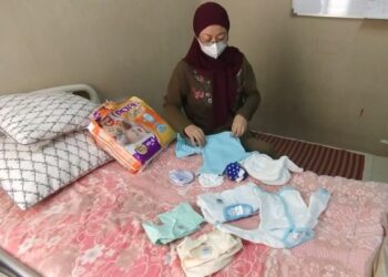 FAZARIAH Nordin melihat pakaian untuk bayi Jahidah di rumah salah seorang lagi kakaknya Fauziah Nordin di Bandar Seri Sendayan, Seremban, semalam. - FOTO/NOR SHAFAWATI YUP