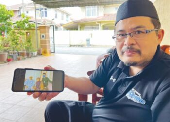 MUSZAIDI Mustafar menunjukkan gambar kenangan Allahyarham bapanya ketika menerima rawatan di hospital pada hari pertama Aidilfitri, baru-baru ini.-UTUSAN/ZAKKINA WATI AHMAD TARMIZI