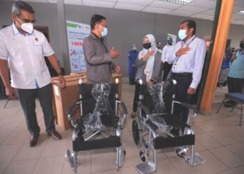 MOHAMAD Taufek Abd. Ghani (dua dari kiri) menyerahkan kerusi roda bagi kemudahan di PPV Kompleks Belia dan Sukan, Paroi, Seremban yang mula beroperasi hari ini.UTUSAN/MOHD. SHAHJEHAN MAAMIN.