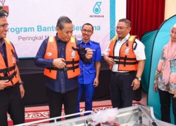 AMINUDDIN Harun (dua dari kiri) mencuba jaket keselamatan sambil diperhatikan Mohd. Nazri (tengah) dan M. Zaki (dua dari kanan) pada Program Bantuan Bencana Petronas di Seremban hari ini.