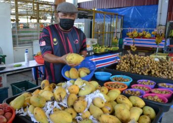 AZMAN Nasir menunjukkan buah-buahan yang dijual di gerai miliknya di Nilai 3, Nilai, Seremban. - UTUSAN/ZAKKINA WATI AHMAD TARMIZI