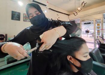 AIMI Amirah Abd. Rahman mendandan rambut seorang pelanggannya ketika ditemui di Batu Kikir, Jempol, semalam. – Mingguan/NURULAZMA SHAFIQAH KHAIRUL AZHAR.