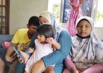 NOR Bainah Mat bersama tiga orang anaknya melihat gambar suaminya, Mohd. Sharil yang meninggal dunia akibat Covid-19 baru-baru ini.-UTUSAN/NOR AINNA HAMZAH.