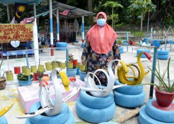 ROHANI Mokhtar menunjukkan landskap halaman rumahnya yang dihias menggunakan barangan terpakai sejak 23 tahun lalu keitka ditemui Utusan Malaysia di Kampung Kemin Tanjung, Jelebu, semalam.-UTUSAN/ZAKKINA WATI AHMAD TARMIZI