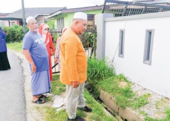 NURHISAM Johari (kanan) meninjau keadaan longkang yang kecil dan sempit yang menyebabkan banjir kilat sering berlaku di RAKR Gong Pasir, Dungun, Terengganu, semalam. – UTUSAN/NIK NUR IZZATUL HAZWANI NIK ADNAN