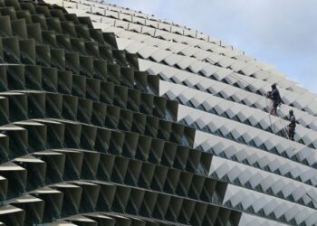 PEKERJA membersihkan kubah Esplanade Theatre di Singapura. - AFP