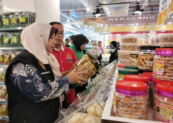 KASEMANI Embong (kiri) memeriksa label tarikh tamat tempoh pada produk makanan yang dijual dalam Ops Pelabelan di sebuah pasar raya di Kuala Terengganu, semalam. - UTUSAN/KAMALIZA KAMARUDDIN