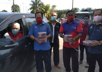 AHMAD Maslan (dua kiri) mengagihkan daging korban secara pandu lalu di Pusat Khidmat Ahli Pontian, di Benut, Pontian, Johor.