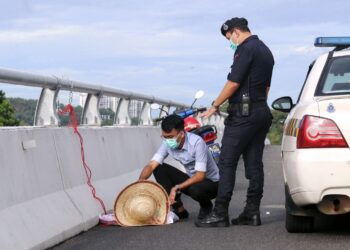 SEPASUKAN anggota polis menurunkan patung bertulisan kerajaan pembunuh yang digantung di sebuah jambatan di Jalan Tun Abdul Razak - Ayer Keroh kira-kira pukul 9 pagi tadi. - UTUSAN/RASUL AZLI SAMAD