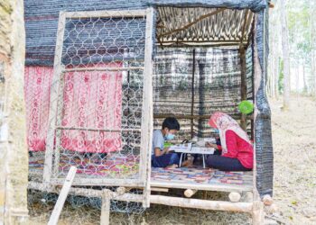 MIMI Izmaliza dan adiknya, Mohamad Izman Malik belajar di sebuah pondok yang dibina bapa mereka di dalam
kebun getah di Kampung Malan, Dangi, Kuala Pilah, semalam. – UTUSAN/ZAKKINA WATI AHMAD TARMIZI
