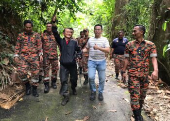 ANGGOTA bomba bersama lelaki (tengah) yang ditemukan hari ini selepas dilaporkan hilang sejak semalam ketika melakukan aktiviti pendakian di Gunung Liang dekat Tanjung Malim. - UTUSAN