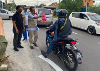 FAKHRUDDIN Mohd.Arif (kiri) menyaksikan Shatiri Mansor (dua dari kiri) menyampaikan pek makanan kepada orang ramai secara pandu lalu di hadapan Koley Park Station Kampung Melayu Subang, Selangor. - UTUSAN / ABDUL RAZAK IDRIS