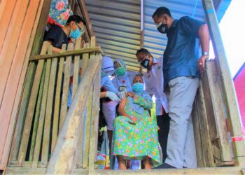 WARGA emas Orang Asli, Zaleha Abdullah menerima suntikan vaksin Covid-19 sambil diperhatikan oleh Abdul Rahman Mohamad(kanan) dan Mohd. Salim Mohd. Sharif (dua, dari kanan) sempena Program Vaksinasi Bergerak Orang Asli di Kampung Panchor, Jempol hari ini.-UTUSAN/MUHAMMAD IZZAT TERMIZIE
