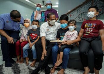 M. Saravanan (tengah) menyerahkan faedah Perkeso ketika menyantuni lima beradik yang menjadi yatim piatu selepas kehilangan ibu bapa mereka akibat jangkitan Covid-19 di Kota Perdana, Seri Kembangan, Selangor. - UTUSAN FARIZ RUSADIO