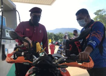 NURUL Amin Hamid (kiri) membantu seorang penunggang motosikal mengisi petrol pada Program Minyak Petrol Percuma di sebuah stesen minyak di Yan, Kedah,  hari ini. - UTUSAN/NUR ANATI JUHARI