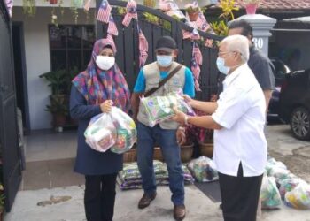 HASSAN Abdul Karim (kanan) menyerahkan bantuan bakul makanan kepada penerima di Taman Kota Puteri di Pasir Gudang, Johor.