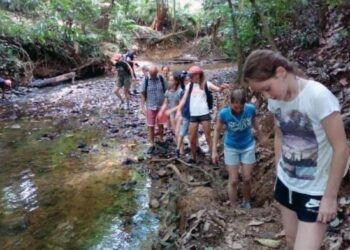 SEKUMPULAN pelancong luar sedang merentasi anak sungai sambil menikmati keindahan hutan tropika berdekatan Kampung Kuala Sat, Ulu Tembeling di Jerantut, Pahang.