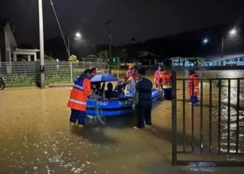 ANGGOTA pasukan keselamatan memindahkan mangsa banjir di Taman Beserah di Kuantan, Pahang. - FOTO/IHSAN APM PAHANG