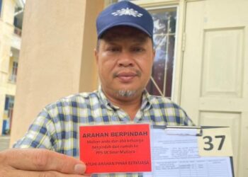 SAMSUDIN Hassan menunjukkan kad yang diserahkan kepada mangsa banjir untuk dipindahkan ke PPS di PPS SK Sinar Mutiara, Kampung Sungai Miang, Pekan, Pahang. - FOTO/NORHAFIZAN ZULKIFLI