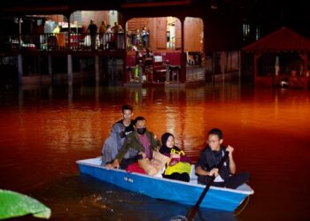 PENDUDUK kampung menaiki bot untuk mencari keperluan selepas rumah mereka dilanda banjir akibat hujan lebat berterusan yang  bertembung dengan air pasang besar di kampung Sri Damai, Kuantan, Pahang. -UTUSAN/ SHAIKH AHMAD RAZIF