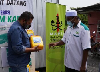 ZUHANIS Zainol (kiri) menunjukkan bekas berisi air sumbangan pihaknya kepada Setiausaha Pertubuhan Kebajikan Islam Malaysia (PERKIM) Kapar, Ustaz Mohamad Razif Ibrahim Muniandy di Kampung Sementa di Kapar, Klang hari ini. - UTUSAN / ABDUL RAZAK IDRIS