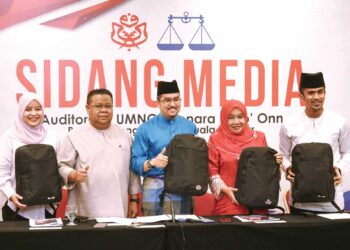 ASYRAF Wajdi Dusuki menunjukkan beg yang akan diberikan kepada perwakilan yang akan menghadiri 
Perhimpunan Agung UMNO minggu depan. – UTUSAN/AMIR KHALID