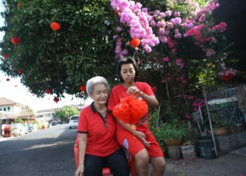 CHEW Cheong Keok ditemani Julli Sulli memegang tanglung sekali gus mengimbau kenangan bersama anak angkatnya yang berlainan kaum yang tidak dapat pulang ke Taman Pengkalan Asam, Kangar, Perlis, sempena sambutan Tahun Baharu Cina kali ini. - UTUSAN/SHAHIR NOORDIN