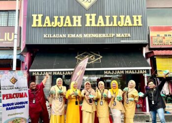 KAKITANGAN kedai emas Hajjah Halijah mengedarkan bubur lambuk percuma sepanjang Ramadan yang menjadi tradisinya sejak 10 tahun lalu di hadapan premis mereka di Jalan Medan, Kangar, Perlis. - UTUSAN/ASYRAF MUHAMMAD