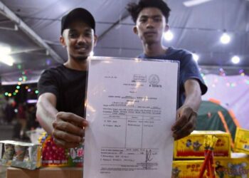 PENIAGA menunjukkan permit menjual mercun dan bunga api di Festival Mega Raya Aidilfitri di Kangar Jaya, Perlis, semalam. - FOTO/IZLIZAN OTHMAN