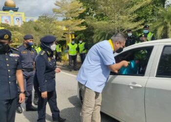 HAMIZAN Hassan menyerahkan bungkusan makanan kepada pengguna jalan raya sempena perasmian Kempen Keselamatan Jalan Raya peringkat negeri ini di Lebuh Raya Changlun-Kuala Perlis hari ini. - FOTO/SYED AZLAN SAYID HIZAR