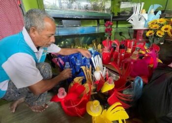 ZULKIFLI Husin menyusun bekas pokok hiasan yang dihasilkannya dengan menggunakan barangan terpakai yang dikutip sendiri di sekitar Kangar, Perlis, semalam.- UTUSAN/IZLIZAN OTHMAN