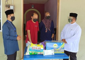 TUANKU SYED FAIZUDDIN PUTRA JAMALULLAIL (kanan) menyantuni asnaf di Simpang Empat, Arau, Perlis semalam.- UTUSAN