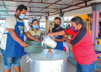 PENDUDUK bersama-sama wakil Era Foods MY mengacau bubur lambuk dalam program Kongsi Berkat Bubur Lambuk dan diedarkan secara percuma kepada orang ramai di Dewan Orang Ramai, Kampung Tengah, Kuala Perlis semalam.– UTUSAN/SHAHIR NOORDIN