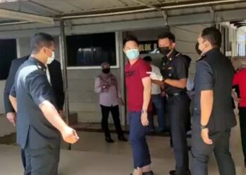 TERTUDUH (baju merah) di bawa keluar dari mahkamah selepas didenda RM80,000 atas kesalahan perdagangan jersi dan seluar tiruan di Mahkamah Sesyen, Kangar, Perlis hari ini.- UTUSAN/NAZLINA NADZARI