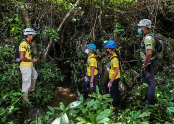AHLI-ahli Perlis Nature and Wildlife (PNW) meninjau keadaan di hadapan laluan masuk ke gua batu kapur yang merupakan salah satu lokasi bekas lombong bijih timah di Wang Ulu, Bintong, Kangar, Perlis, semalam.
– UTUSAN/ SHAHIR NOORDIN