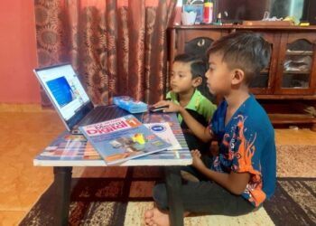 MOHD. Adha Nor Irwan (kanan) serta adiknya, Mohd. Risqi berkongsi komputer riba untuk belajar secara dalam talian dalam proses pengajaran dan pembelajaran di rumah (PdPR) di Kampung Lama, Guar Sanji, Arau, Perlis. - UTUSAN/MOHD. HAFIZ ABD. MUTALIB