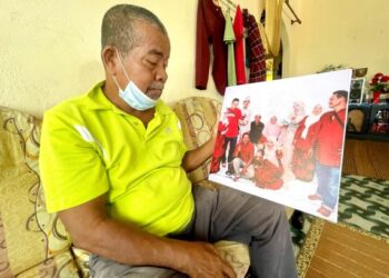 BAGI mengubati kerinduan anak-anak dan cucu tidak dapat pulang ke kampung halaman bagi menyambut Aidilfitri, Saadan Ismail berulang kali menatap gambar anak-anaknya di Kampung Sungai Padang, Simpang Empat, Arau. – FOTO/NAZLINA NADZARI