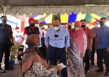 MUHYIDDIN Yassin bersama isteri, Puan Sri Norainee Abdul Rahman berbual dengan seorang penerima vaksin yang sedang menunggu giliran di PPV Dewan Muafakat Bukit Gambir, Tangkak, Johor, semalam. - UTUSAN/NUR ALINA HASSAN