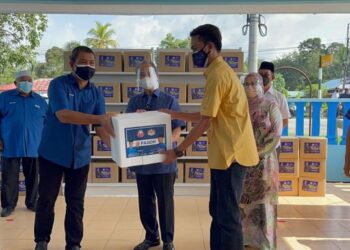 MUHYIDDIN Yassin (tengah) menyampaikan bantuan bakul makanan kepada penghulu untuk diberikan kepada keluarga yang sedang dikuarantin di Kompleks Penghulu Mukim Sungai Raya di Bukit Pasir, Muar, Johor. - FOTO/NUR ALINA HASSAN