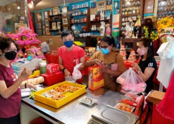 SUNNY Quah (dua dari kiri) melayan pelanggan yang membeli kuih di kedainya di Teluk Intan, Perak sempena sambutan Tahun Baharu Cina. - UTUSAN/AIN SAFRE BIDIN