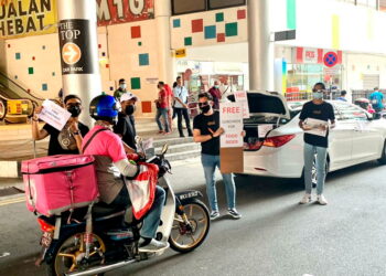 KAKITANGAN Mat Salleh Barber mengagihkan pek nasi tomato secara percuma sebagai tanda penghargaan kepada barisan hadapan yang terlibat dalam mengekang wabak Covid-19 di sekitar pusat bandar Georgetown, Pulau Pinang semalam. - UTUSAN/NOOR HASLIZA NUSI