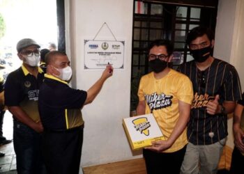 SAARANI Mohamad (kiri) menandatangani plak lawatan pada program Lawatan Mesra Usahawan Perak di Miker Pizza, Ipoh, Perak, hari ini. - FOTO/ZULFACHRI ZULKIFLI