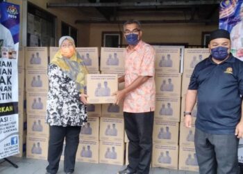 MUSTAPA Kamal (tengah) menyampaikan sumbangan kotak makanan kepada Rosmunah Hamdan di Bukit Gantang semalam. - UTUSAN/WAT KAMAL ABAS