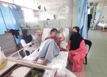 Rohani Awang Ngah menemani M. Daud Kilau di Hospital Teluk Intan, Perak, semalam. - UTUSAN/AIN SAFRE BIDIN