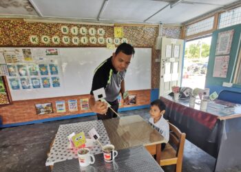 MOHAMAD Danish Harraz Mohd. Anuar murid Tahun 1 yang mendaftar di SK Tebing Rebak bersama gurunya. - UTUSAN/AIN SAFRE BIDIN