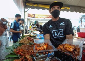 SEORANG peniaga menunjukkan juadah mee tonggek udang galah dan sotong di Bazar Ramadan Putrajaya Presint 3, Putrajaya. - UTUSAN/FAISOL MUSTAFA