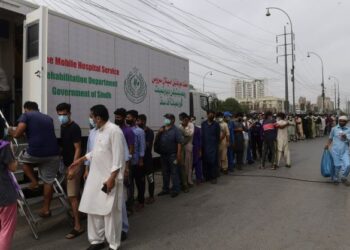 PENDUDUK beratur untuk mendapatkan suntikan vaksin Covid-19 di luar sebuah van yang diubah suai menjadi pusat vaksinasi bergerak di Karachi, Pakistan. - AFP