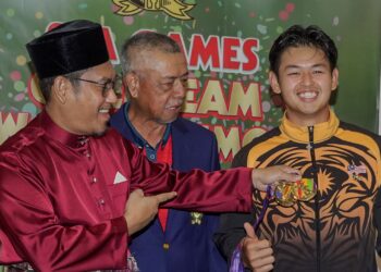 AHMAD Faizal Azumu (kiri) melihat pingat emas yang dimenangi Ervin Chang pada majlis penghargaan hari ini. - UTUSAN/ AMIR KHALID